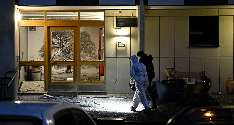Det är mörkt ute. Två poliser är vid ett hus där någon har sprängt.