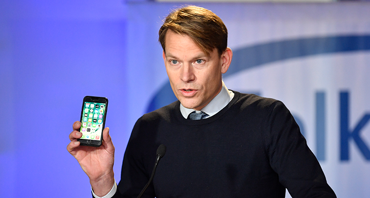 Han håller i en mobiltelefon.