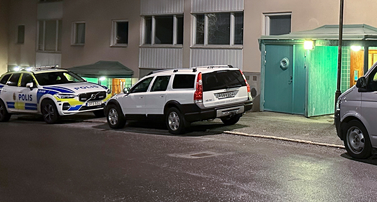 Polisbil parkerad utanför ett hyreshus.