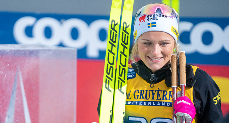 Karlsson har skidorna i handen och ler.