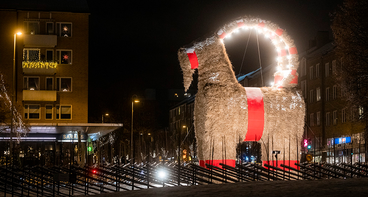 En stor bock av halm står i mörkret på ett upplyst torg