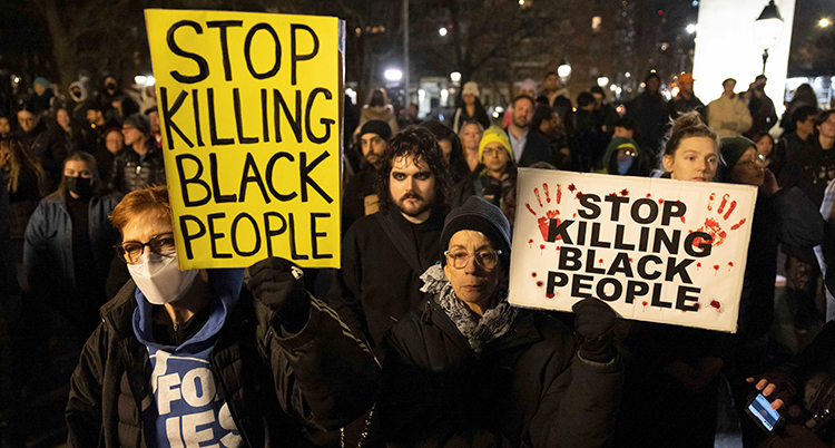 Människor är samlade utomhus i mörkret, Några håller upp skyltar där det bland annat står Stop killing black people.
