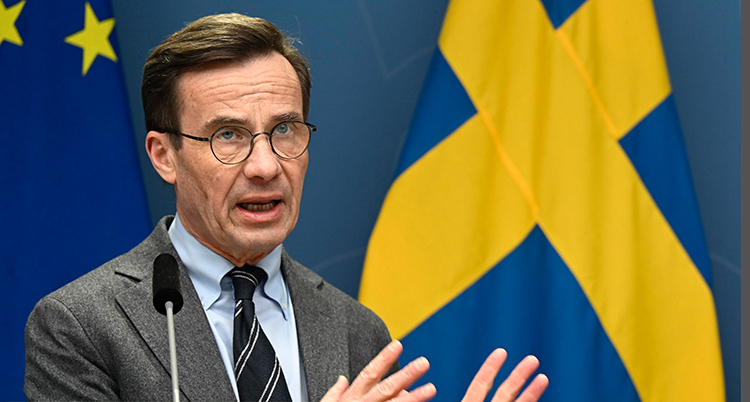 Han har glasögon, kostym och slips.