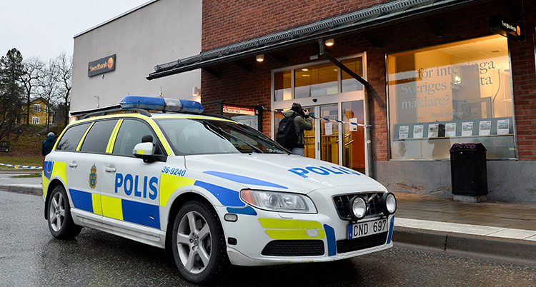 En polisbil står framför en bank.