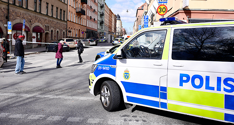 Poliser har spärrat av en gata. Det står flera polisbilar där.