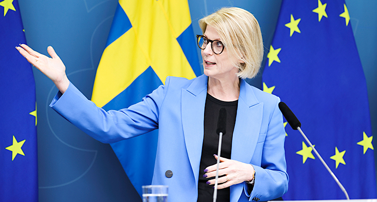 Hon står och pratar i en mikrofon på en träff med journalister.