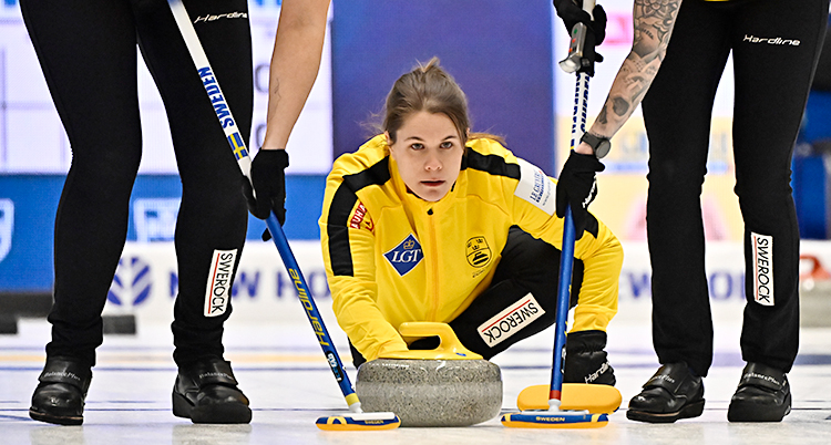 Hon skickar iväg en sten i en match i curling.