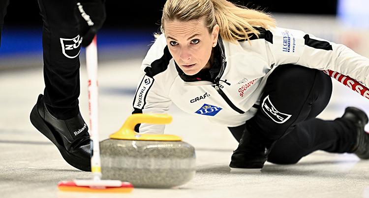 Hon skickar iväg en sten i curling.
