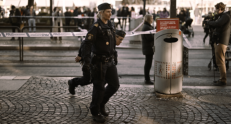 Poliser går på gatan. De har satt upp tejp.