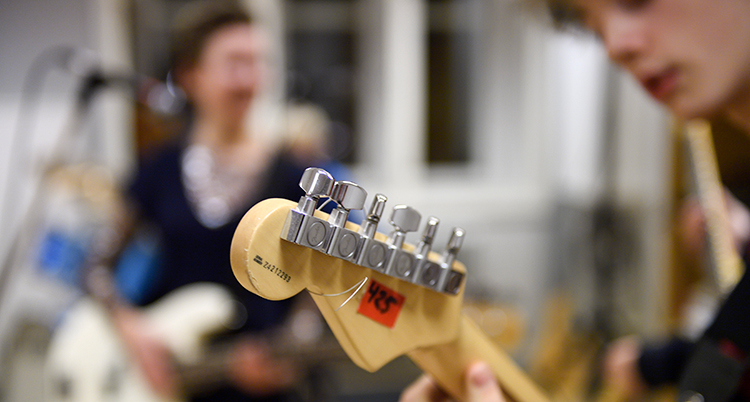 en ung person spelar gitarr.