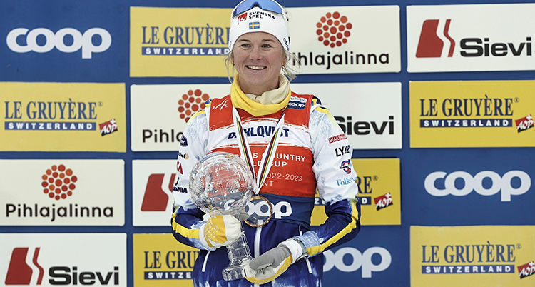 Hon har mössa och skidkläder. Hon håller i ett pris.