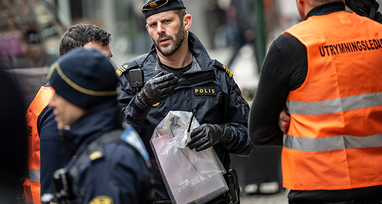 En polis med en påse i handen.