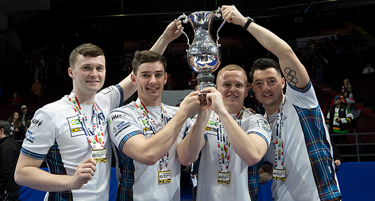Fyra män är glada och står med en pokal.