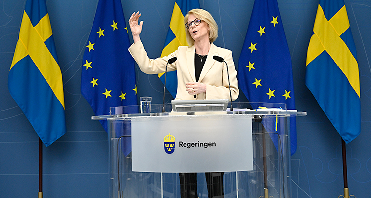 Hon står och pratar i en mikrofon på en träff med journalister.