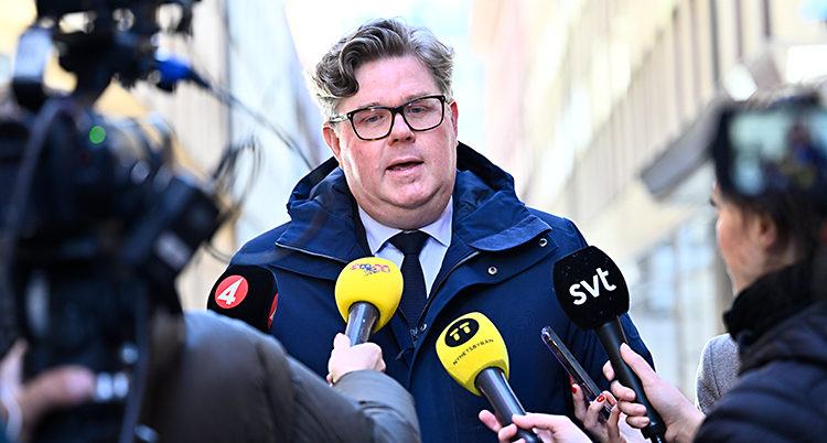 Han står och pratar i journalisternas mikrofoner.