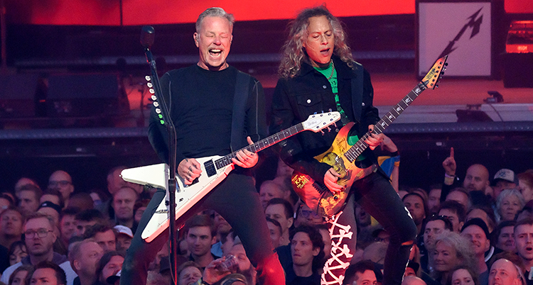 De står på en scen och spelar gitarr.