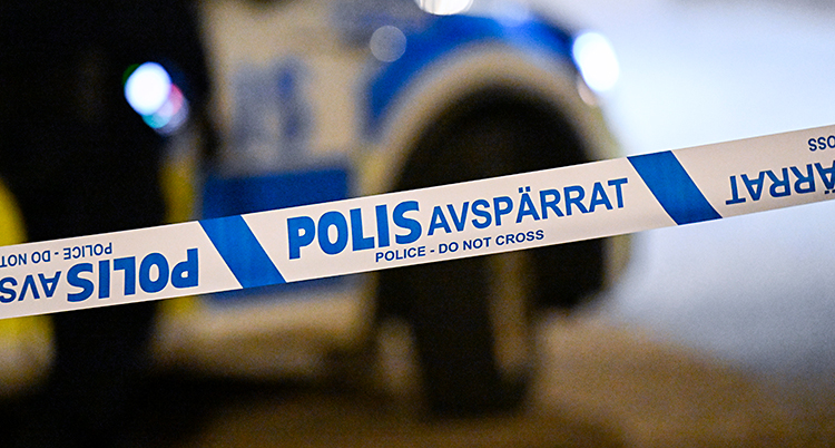 Det är kväll. Poliser har spärrat av med ett band.