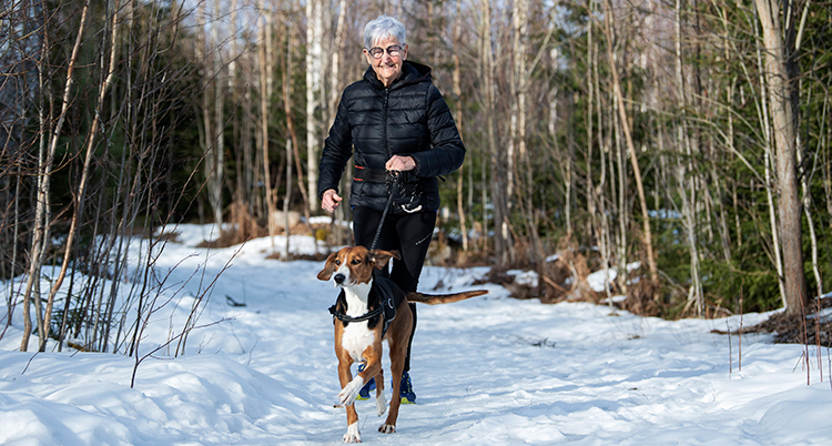 Hon springer på snö med en hund.