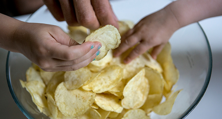 tre händer som tar chips ur en skål.
