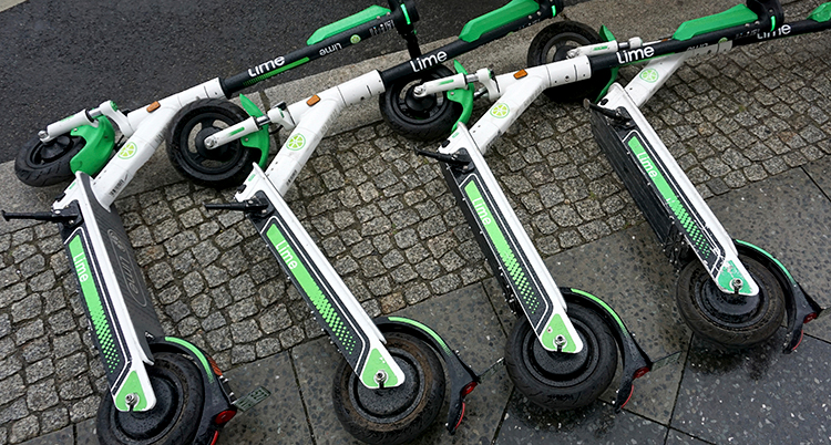 Flera sparkcyklar ligger ner på en gata.