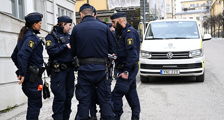 Poliser framför en vit bil.