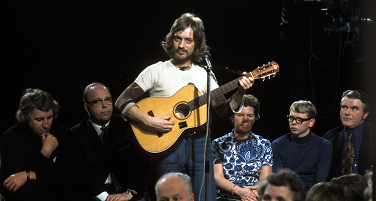 Han spelar gitarr i ett program i tv.