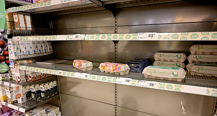 Två hyllor i en affär. På en av hyllorna är det helt tomt. På den andra hyllan är det bara några få förpackningar kvar.
