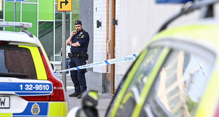 En polis syns och två polisbilar.