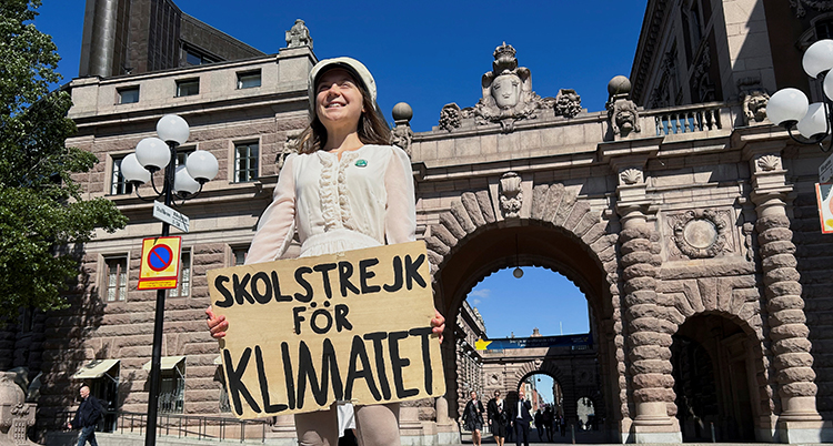 Hon har vita kläder och en studentmössa.