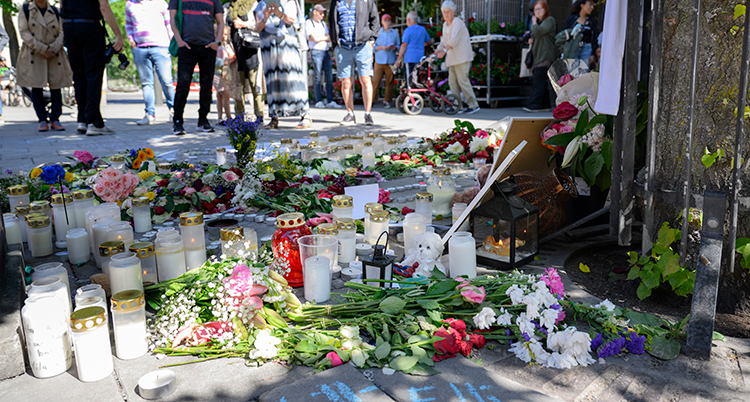 Blommor och ljus syns på platsen.