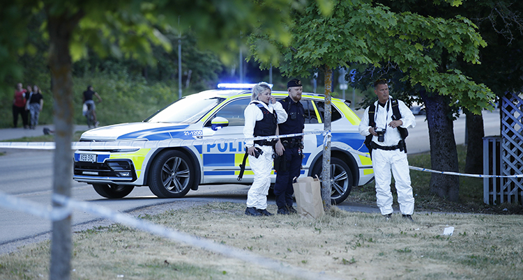 Tre personer framför en polisbil. Två har vita kläder, en har uniform.