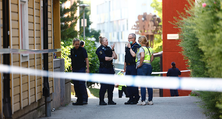 En avspärrad gata vid ett hus. Ambulanspersonal syns också i bilden.