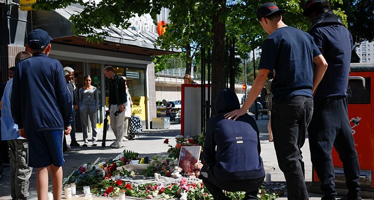 Unga står runt en plats med blommor och ljus.