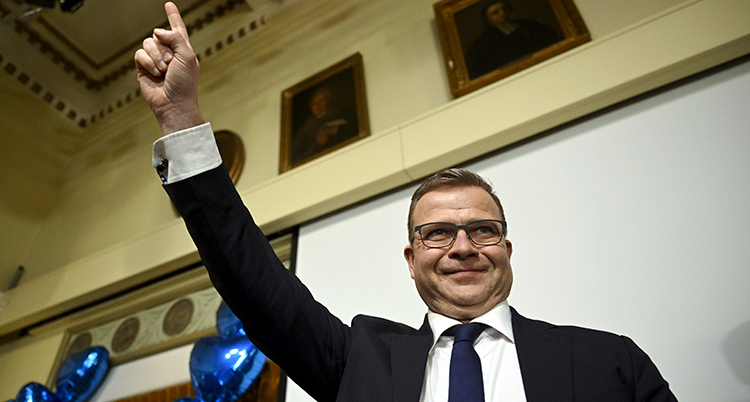 Orpo håller upp ett finger i luften och ler.