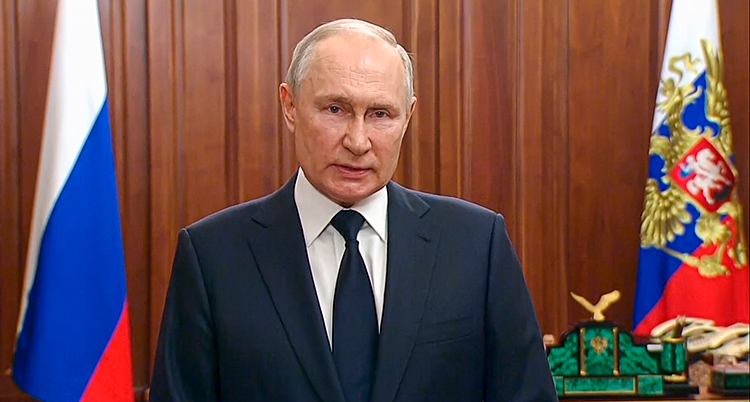 Putin framför två flaggor.