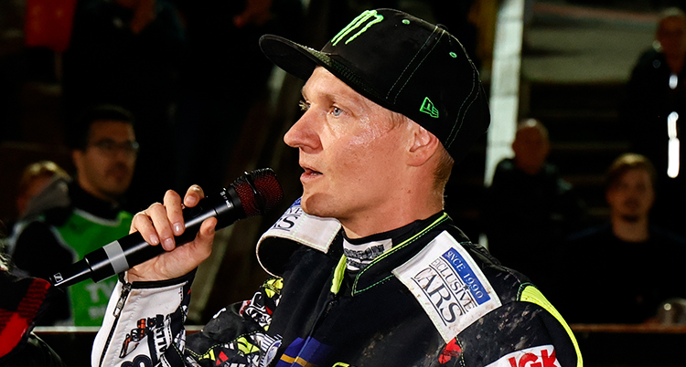 Fredrik Lindgren i keps pratar i mikrofon.