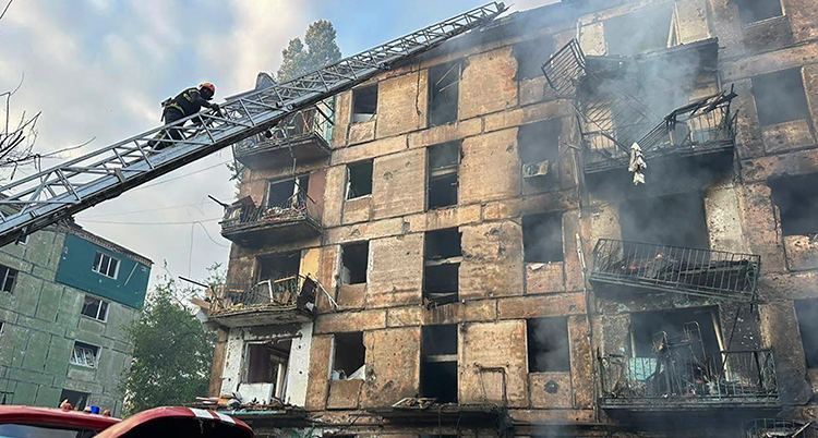 Ett hus är skadat. En stege från en bil är lyft mot huset.