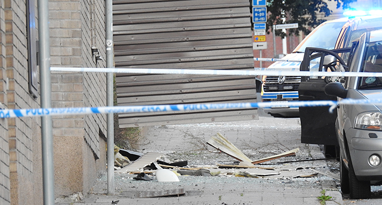 Det ligger skräp och bråte utanför huset efter explosionen. Flera polisbilar är där.