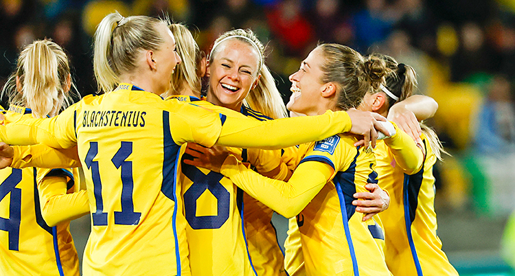 Spelarna kramar varandra efter ett mål i fotboll. De har gula tröjor.