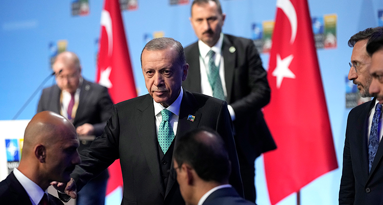 Han går ner från en scen. I bakgrunden syns Turkiets flaggor i rött och vitt.