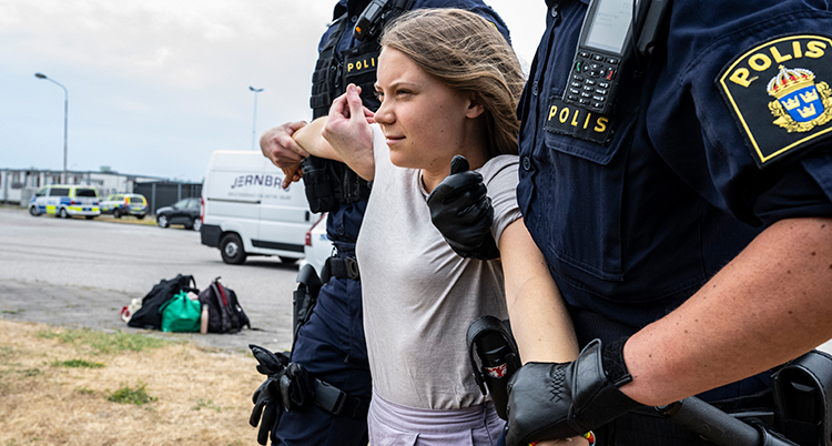 Poliserna håller henne i varsin arm.