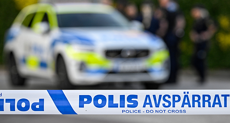 Plastband från polisen med polisbil i bakgrunden.