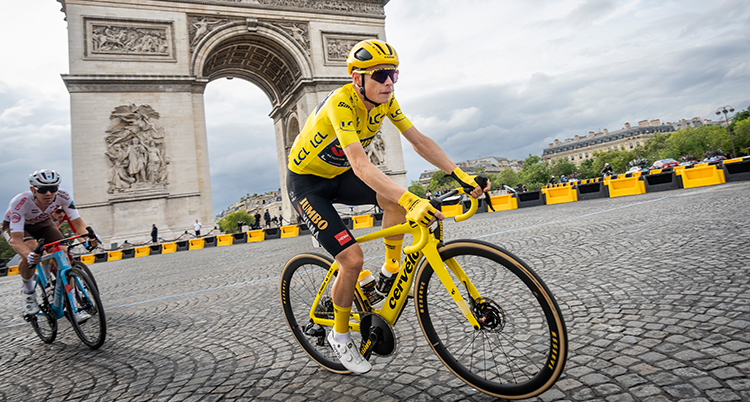 Han cyklar på en kulelrstensgata framför Triumfbågen i Paris