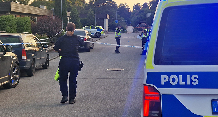 Poliser drar plastband över gata.
