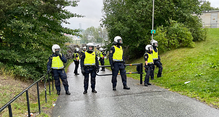 Flera poliser står på en cykelbana. De har skyddskläder och hjälmar.