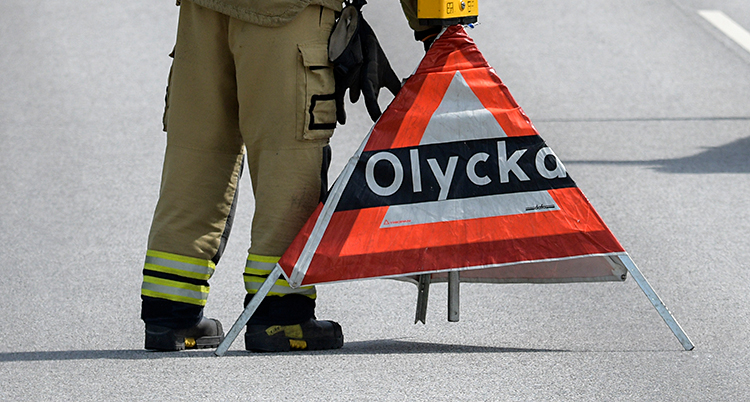 En person från räddningstjänsten ställer ut en skylt som varnar för olycka.