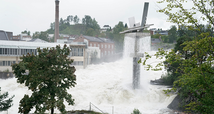 Massor av vatten forsar framför några hus.