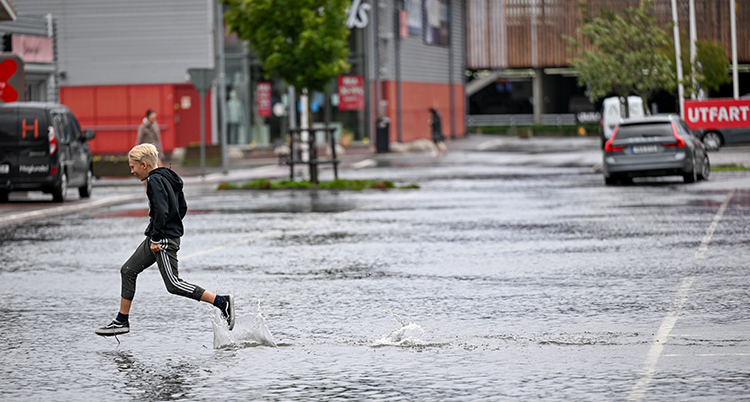 En pojke hoppar över en vattenfylld gata.