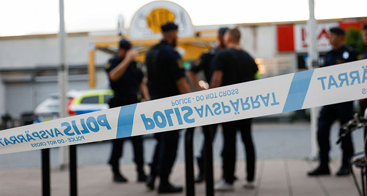 Flera poliser bakom ett blåvitt polisband.