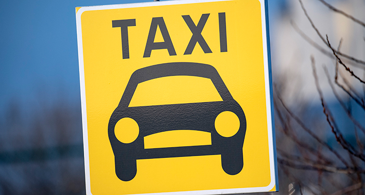 En gul skylt med en taxibil på. Det står också ordet taxi ovanför bilen.